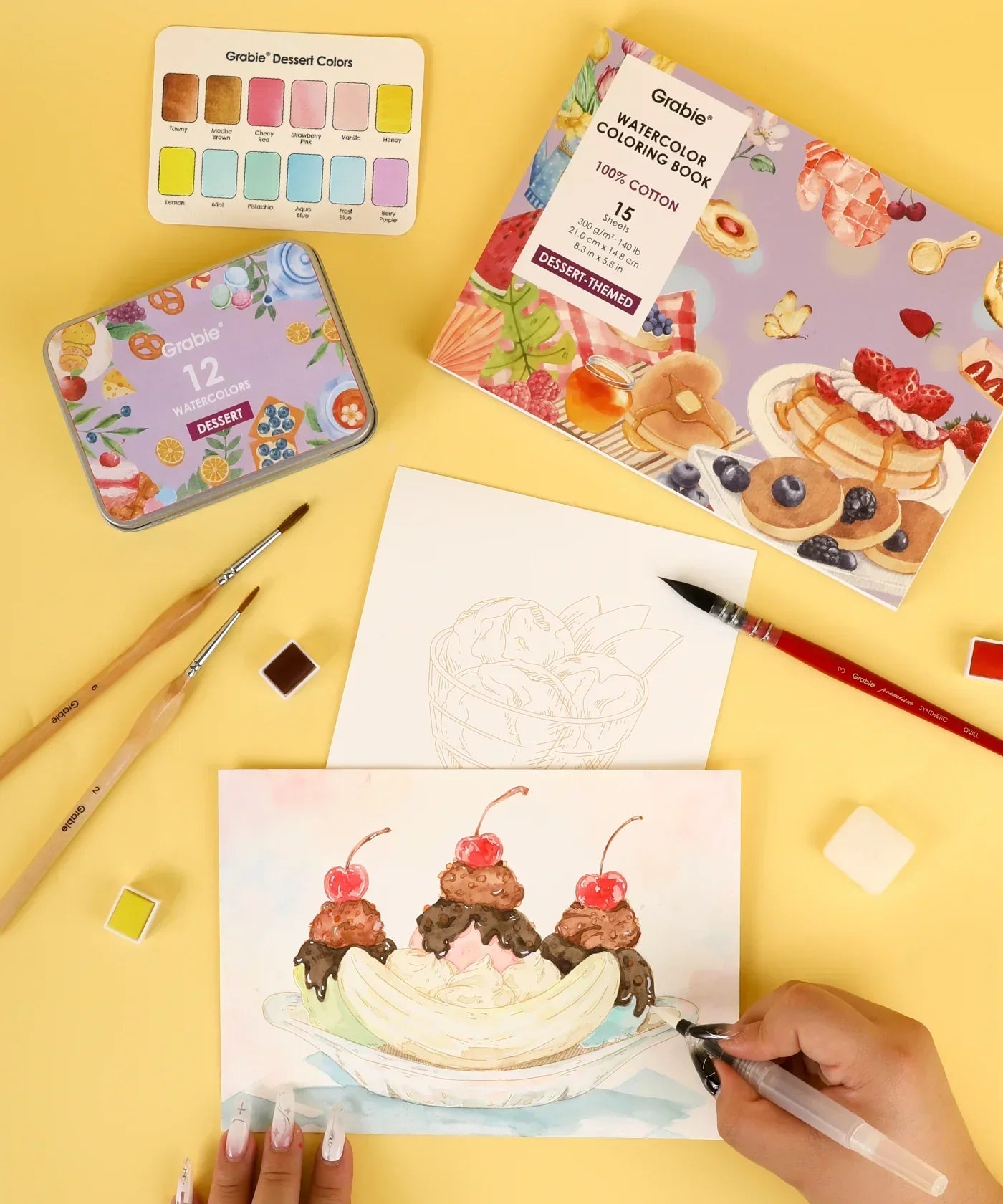 Hand painting a dessert watercolor scene with brushes and paints from Grabie Quarterly Watercolor Coloring Club set