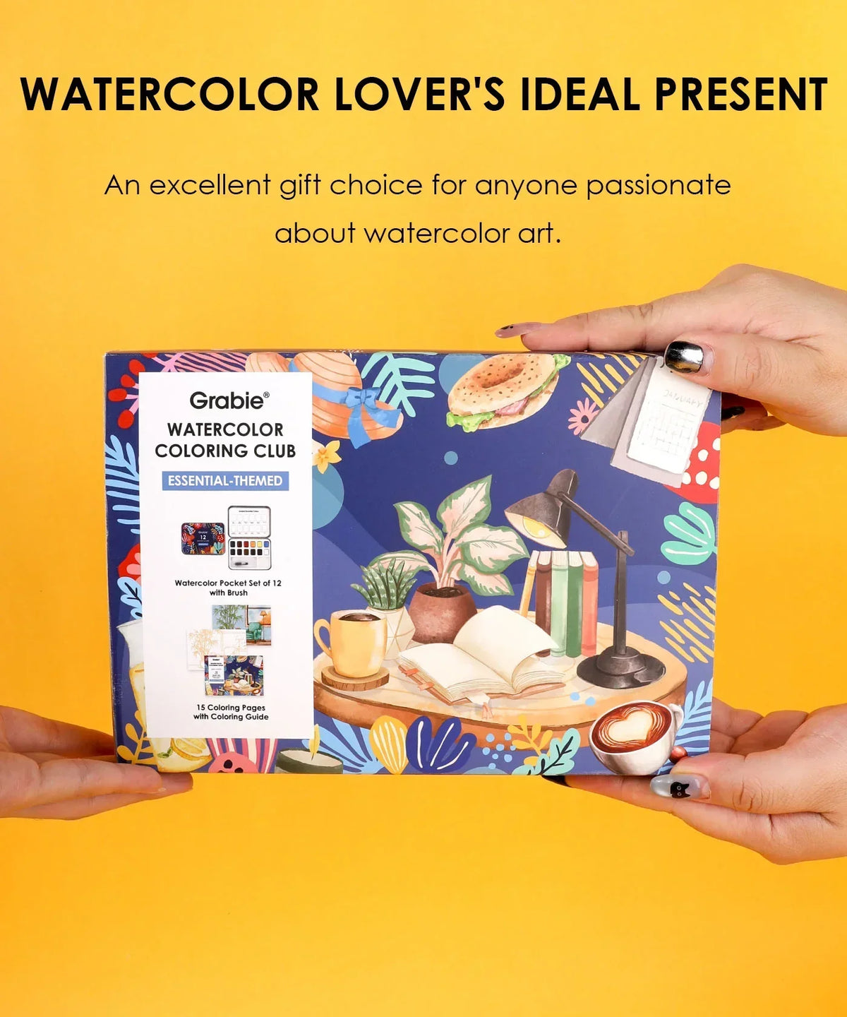 Hands holding Essential-Themed Watercolor Coloring Club Box with artistic designs and watercolor art supplies against yellow background