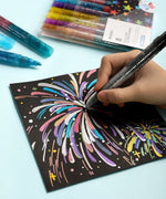 Iridescent Glitter Acrylic Paint Marker Set being used to create colorful sparkling fireworks on black paper with art supplies nearby