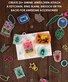 Colorful handmade shrink plastic charms displayed with keychains and rings from the Shrink to Sparkles Craft Kit (DIY Shrinky Dinks Set)