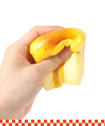 Hand squeezing bright yellow and orange Grabie Ultimate Stress Relief Squishy toy against white background