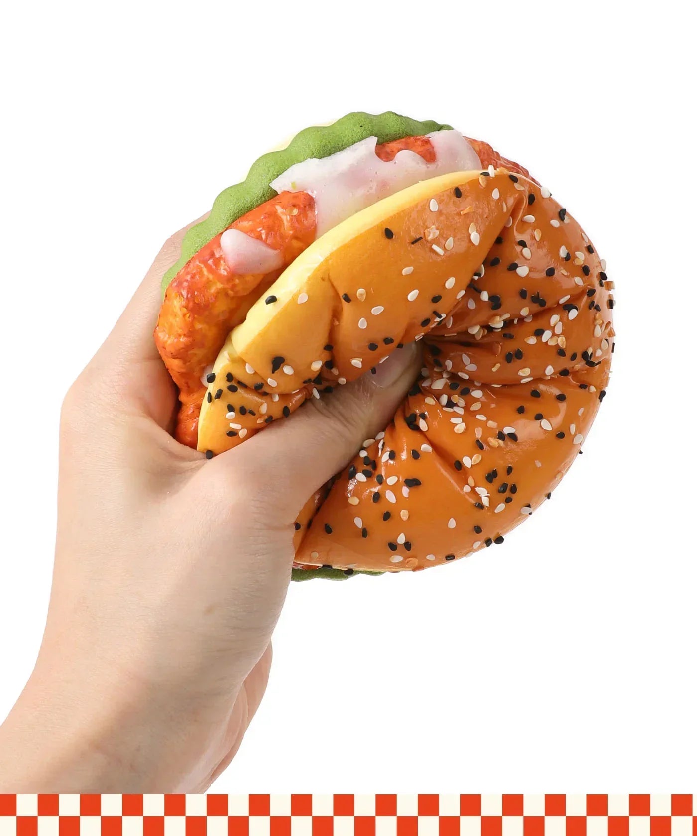 Hand squeezing a realistic burger-shaped Grabie Ultimate Stress Relief Squishy with sesame seed bun and toppings