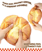 Hands squeezing a realistic bread-shaped Grabie Ultimate Stress Relief Squishy with soft, pillowy texture and fun design