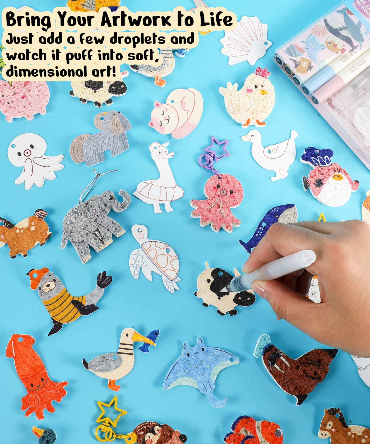 Hand using marker on puffed animal art pieces made with Drop to Puff 3D Sponge Art Kit on blue surface