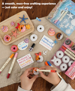 Hands coloring small sea-themed magnets using markers with Magnet Painting Kit (DIY Refrigerator Magnet Kit) packaging nearby 