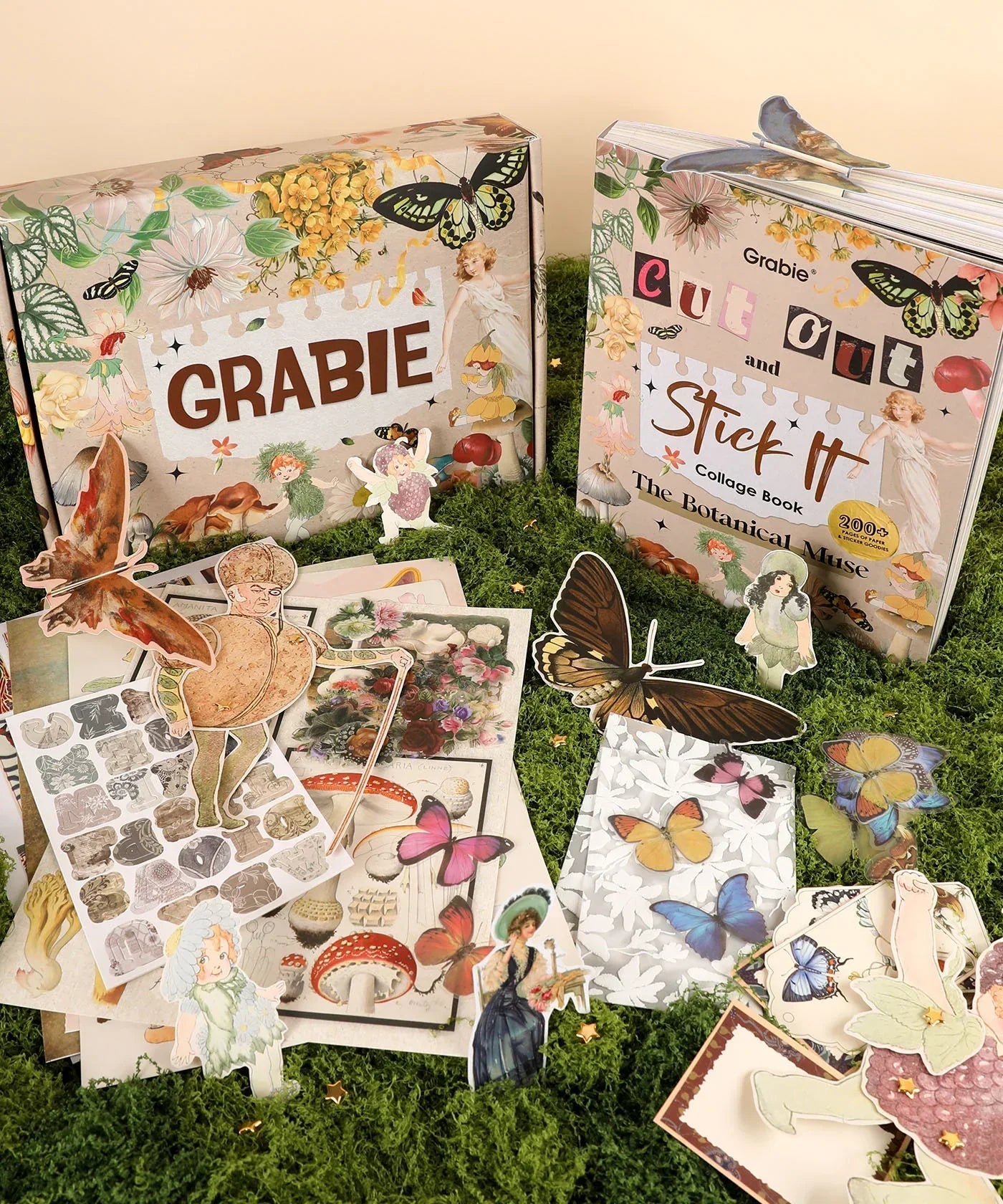 The Botanical Muse-Themed Grabie Scrapbook Club Box with botanical cutouts, butterfly stickers, and collage art supplies on moss.