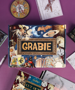 Grabie Scrapbook Club Box with celestial and mythological art supplies and scrapbook materials on a purple background