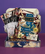 Grabie Scrapbook Club Box open with collage book, assorted vintage art supplies, papers, and stickers for creative scrapbooking.