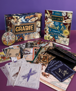 Grabie Scrapbook Club Box with vintage art supplies including collage book, art prints, postcards, and pens on purple surface