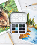 Watercolor Pocket Set of 12 - Forest Colors with paintbrush and nature-themed watercolor artwork on white surface.