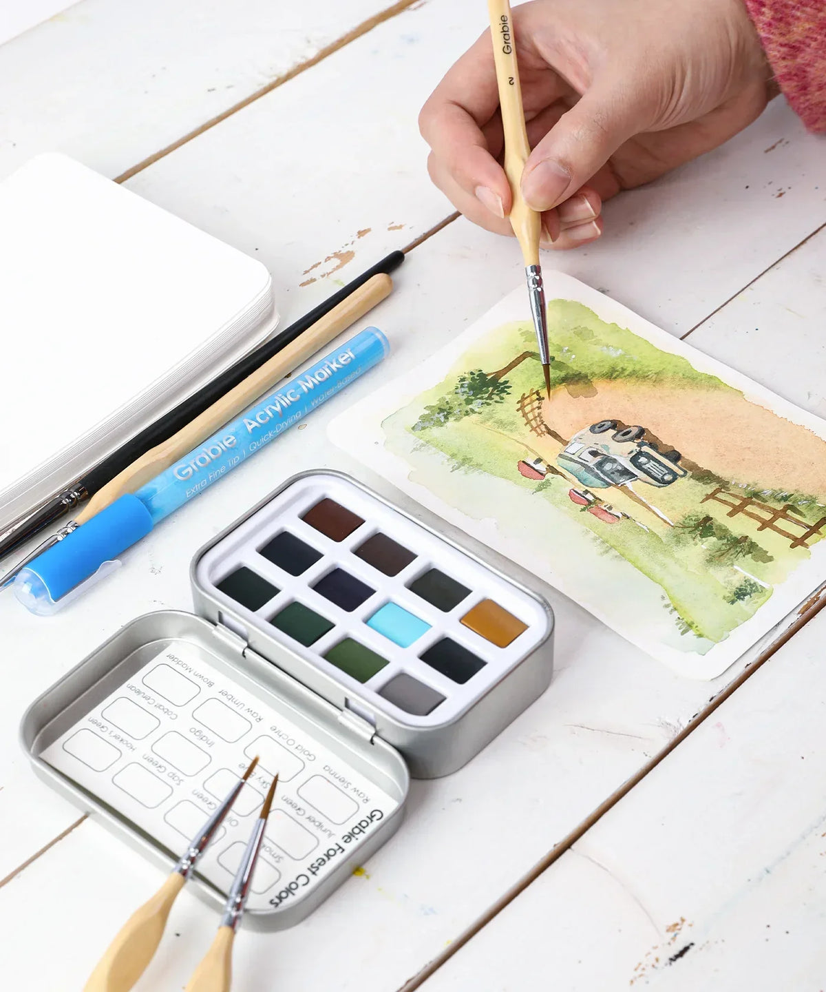 Watercolor Pocket Set of 12 - Forest Colors being used for painting a landscape with brushes and art supplies nearby