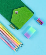 Let Your Feelings Flow Grabie Art Club Box with colorful pencils, eraser, sharpener, and green felt pouch on blue background