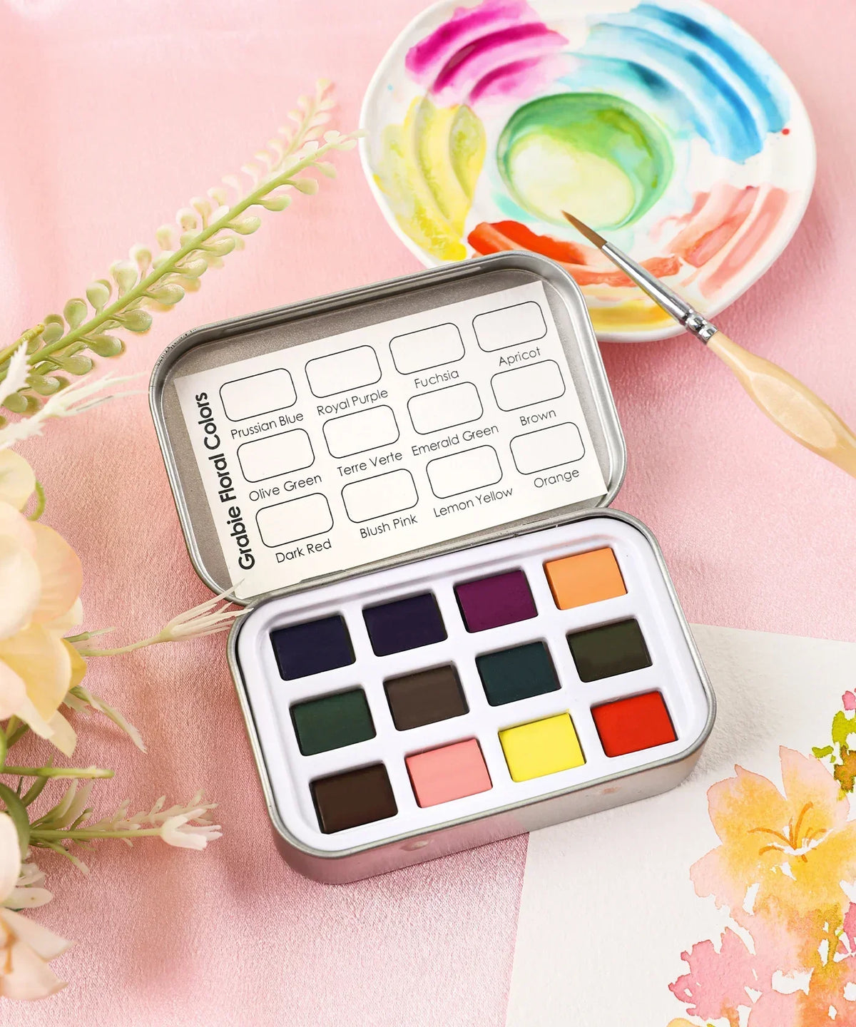 Watercolor Pocket Set of 12 - Floral Colors with vibrant paint pans and a brush on a pink fabric background