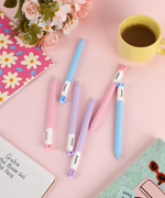 Mindful Bloom gel pens arranged on a cute pink desk setup next to a coffee cup and floral journal.