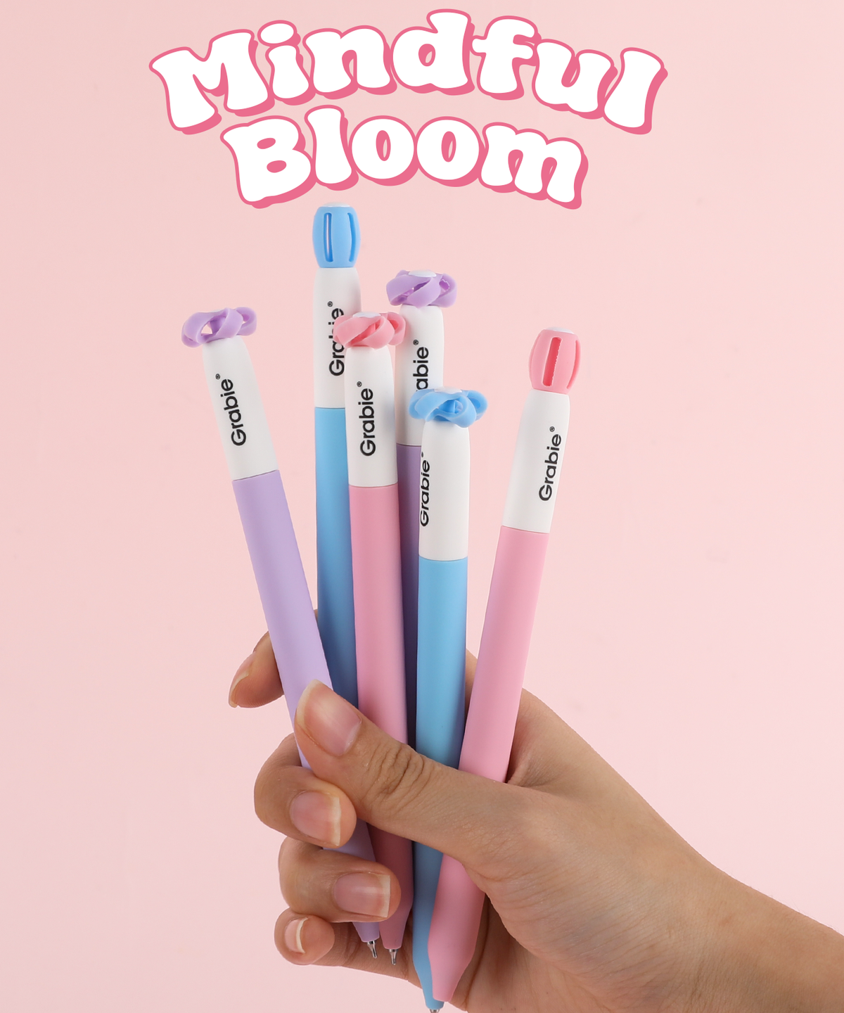 Hand holding a bouquet-like set of 6 Grabie Mindful Bloom novelty pens with blooming flower caps.   