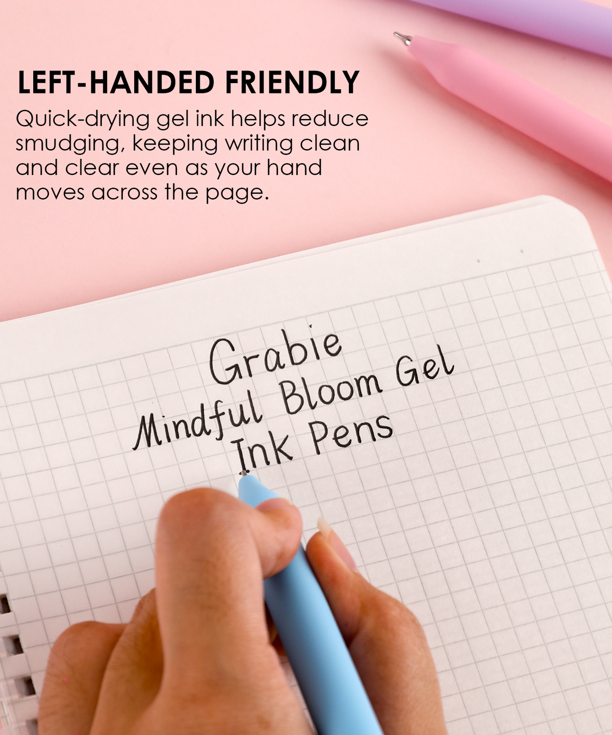 Left hand writing smoothly in a grid notebook using a blue Mindful Bloom quick-drying black ink gel pen.
