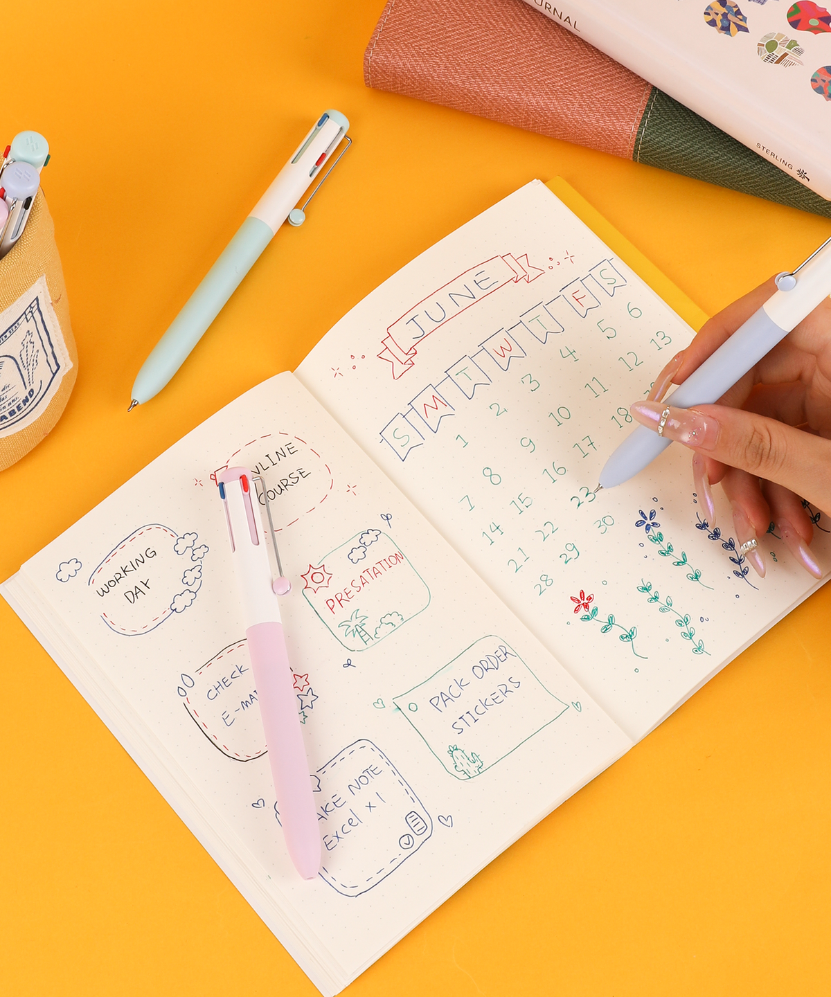 Hand writing in a monthly calendar planner using a pastel multi color pen with color-coded daily tasks.