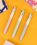 Set of 3 pastel 4 color pens in pink, light blue, and lavender lying neatly on a bright yellow surface.