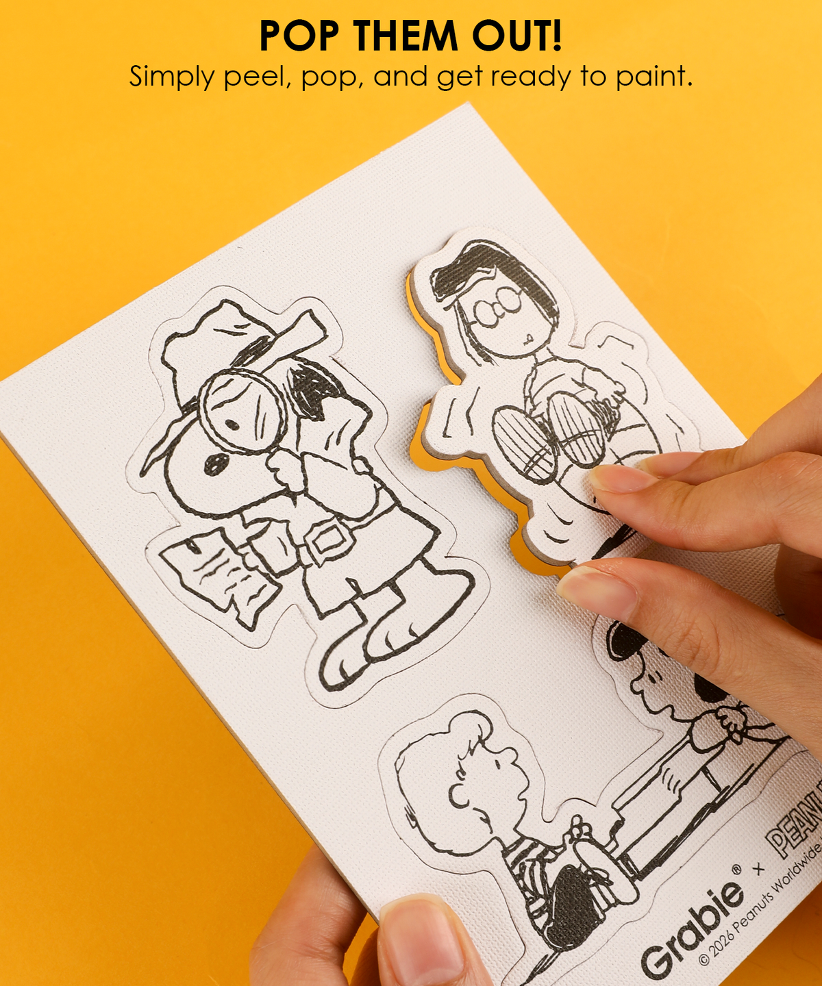 Hand peeling detective Snoopy from the pop-out canvas sheet ready for painting DIY magnets.