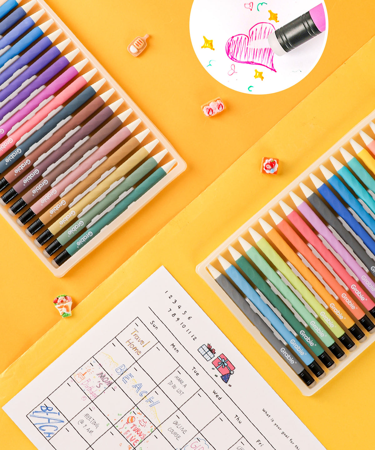 Erasable gel pens next to a drawn monthly planner with a inset circle showing heart drawing being erased.