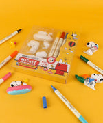 Overhead view of the Snoopy Sweet Days magnet painting kit with colored resin figures and markers spread on a table.
