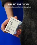 Hand holding a 12 color watercolor travel set with illustrated box, ideal for artists on the go